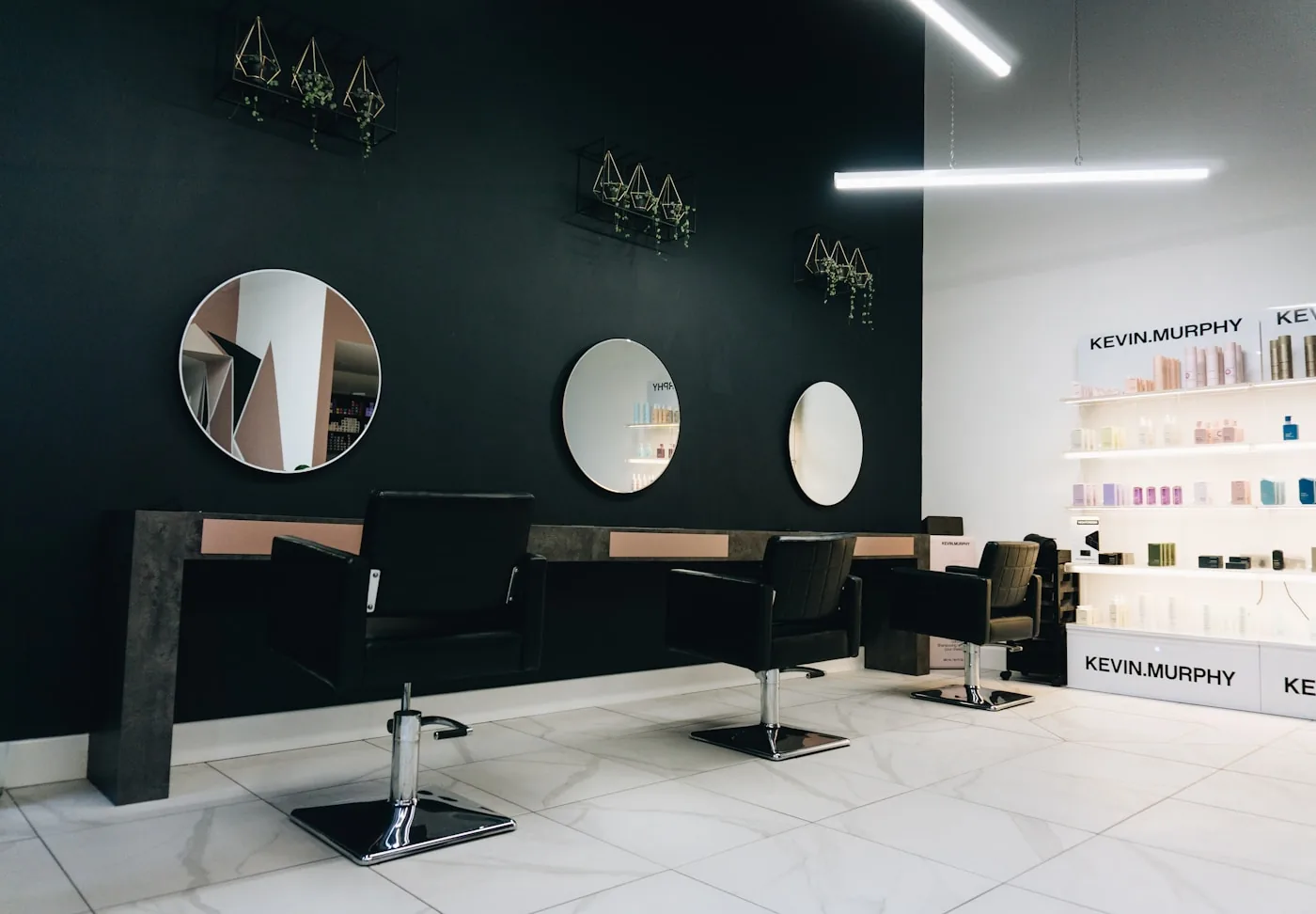 The studio: dark walls, round brass-rimmed mirrors, and a single styling chair