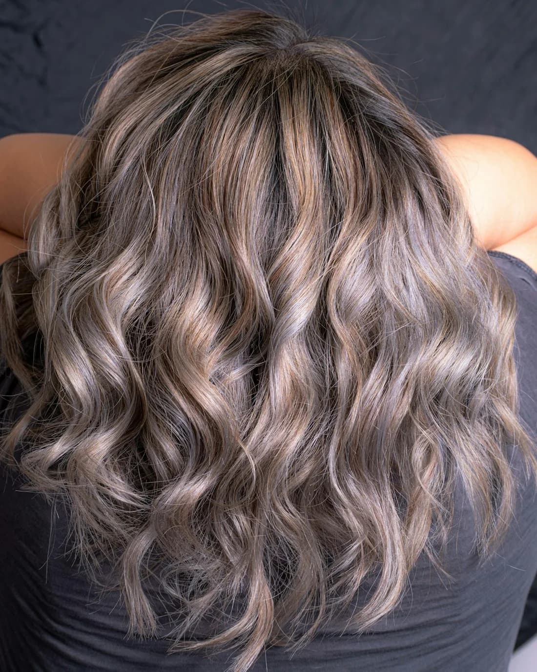 Dimensional ash-blonde waves against a dark backdrop
